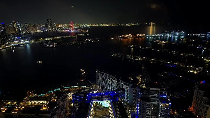Dubai's coastline and Palm Jumeirah at night, seen from a high floor