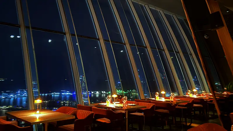 A restaurant in Dubai at night with floor-to-ceiling windows over the water